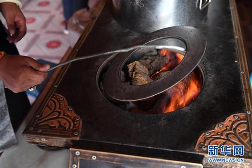 在青海省玉树藏族自治州治多县治渠乡同卡村，村民布沙措江卓玛给家中的炉子添加燃料——牛粪（9月12日摄）。在当地，清洁环保的牛粪依然是不少牧民选用的主要燃料。新华社记者 孙瑞博 摄