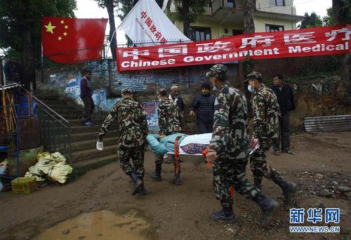2015年4月28日，在尼泊尔首都加德满都以北30公里的杜里凯尔镇，尼泊尔士兵运送一名伤者到中国政府医疗队接受救治。尼泊尔25日中部地区发生8.1级强烈地震，中国政府医疗队27日早抵达尼首都加德满都后立即为灾民提供医疗救援。 新华社发（普拉塔普·塔帕摄）
