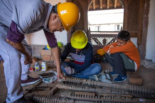 2019年10月10日，在尼泊尔加德满都杜巴广场，中国文物修复师周建国(左)在九层神庙修复现场指导尼泊尔工人。新华社记者张可任摄
