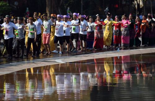 人们在云南省西双版纳傣族自治州景洪市围绕泼水广场中央的水池跳团结舞（2018年4月15日摄）。