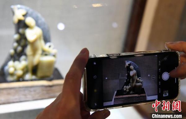 由中国工艺美术大师郑幼林创作的寿山石雕作品《天使归来》，吸引观众用手机拍照。　记者刘可耕 摄