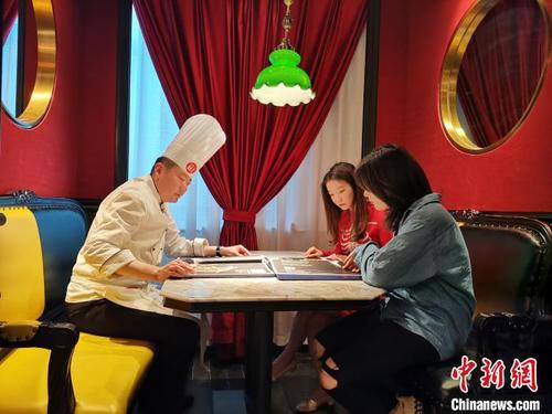 5月24日，记者在济南一鲁菜馆见到网络主播李頔时，她正在餐馆中向厨师了解当天所要进行“吃播”的鲁菜菜式、文化及用料选材方面的讲究。　郝学娟 摄