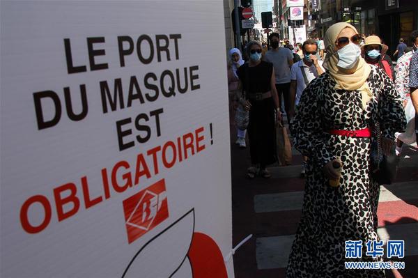 8月5日，购物的人们经过比利时布鲁塞尔市中心的一个佩戴口罩提示牌。 时下正值比利时打折季，布鲁塞尔市政府近日在人流密集的街道设立提示牌，要求民众必须佩戴口罩。 新华社记者郑焕松摄