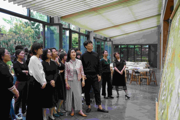 姚建萍（前排右四）、李博文（前排右三）以及设计师、绣娘们一起研读刚刚完成的作品