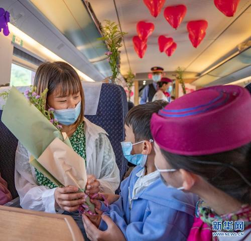 5月8日，在万州北开往重庆北的C6407次列车上，小旅客为妈妈送上鲜花。新华社记者 黄伟 摄