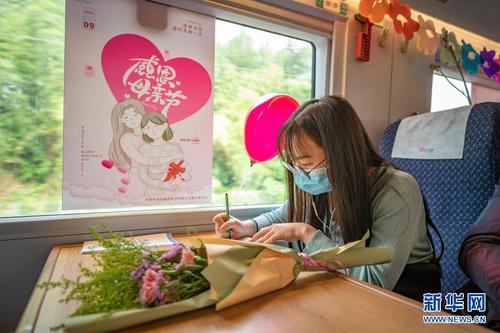 　5月8日，在万州北开往重庆北的C6407次列车上，旅客为母亲写祝福卡片。新华社记者 黄伟 摄