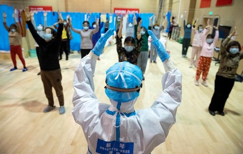 2020年2月25日，在江夏方舱医院，湖南中医药大学第一附属医院医护人员易琴（前）带领新冠肺炎患者习练八段锦。新华社记者 沈伯韩摄