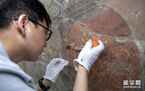　来自敦煌研究院文物保护技术服务中心的文物修复专家在对永乐宫壁画进行修复（6月21日摄）。新华社发