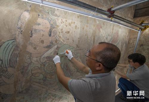 来自敦煌研究院文物保护技术服务中心的专家在对永乐宫壁画进行修复（6月21日摄）。新华社发