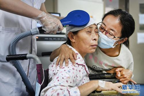 杨竹梅（右）脸贴着母亲的脸，安慰治疗中焦急不安的妈妈（6月22日摄）。新华社记者 陶明 摄