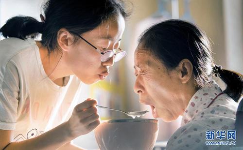 杨竹梅（左）耐心地哄母亲进食（6月22日摄）